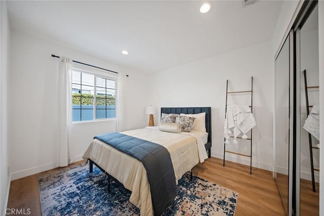 bedroom with a closet, recessed lighting, baseboards, and wood finished floors