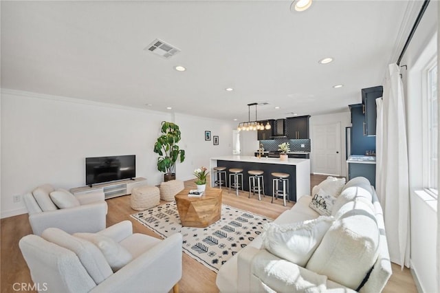 living room featuring visible vents, recessed lighting, light wood-style floors, and ornamental molding
