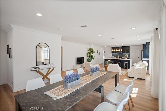 dining room with visible vents, crown molding, baseboards, light wood-type flooring, and recessed lighting