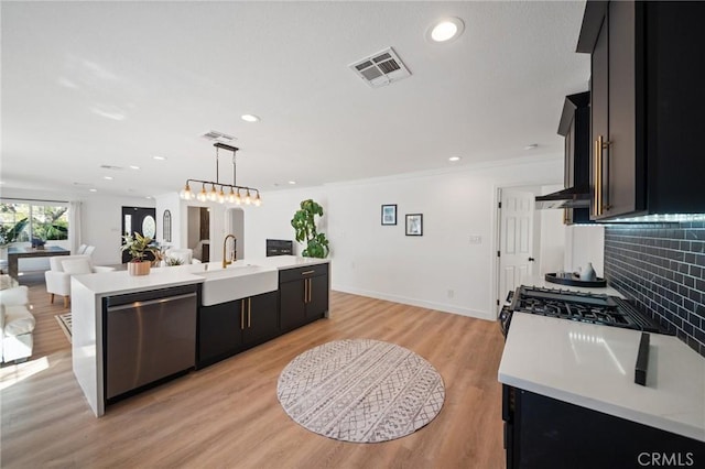 kitchen with visible vents, a sink, stainless steel dishwasher, dark cabinetry, and light countertops