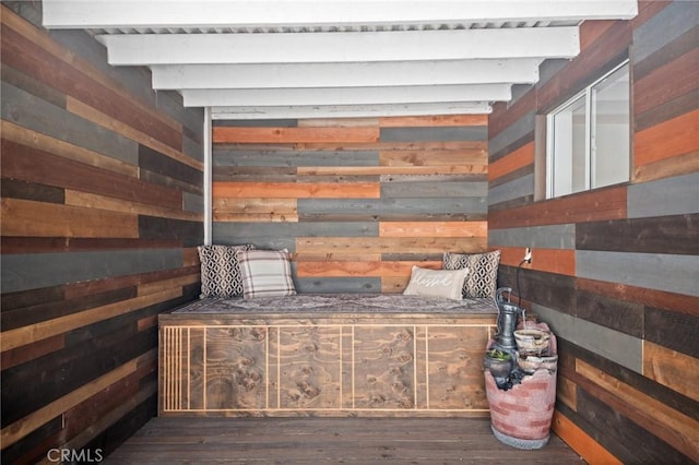 bedroom featuring beamed ceiling, wooden walls, and hardwood / wood-style floors