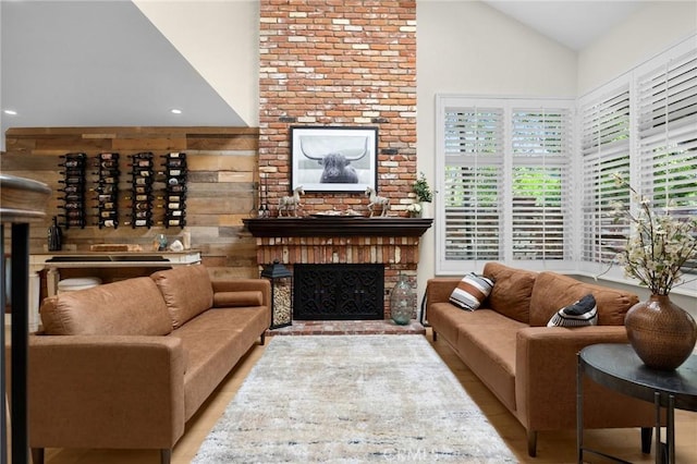 living area featuring high vaulted ceiling, recessed lighting, a fireplace, and wood finished floors