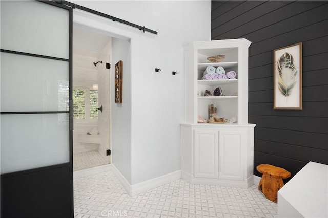 full bathroom with wooden walls, a tile shower, and baseboards