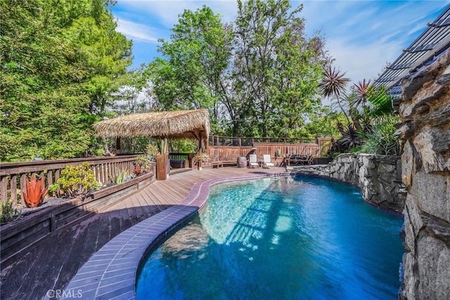 view of swimming pool featuring a gazebo, a wooden deck, a fenced in pool, and fence