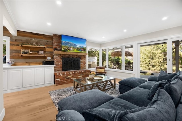 living area with wood walls, a wealth of natural light, light wood finished floors, and a fireplace