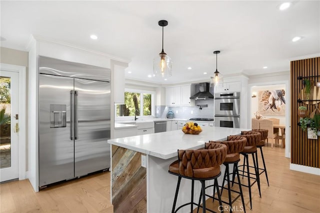 kitchen featuring tasteful backsplash, wall chimney range hood, appliances with stainless steel finishes, crown molding, and white cabinetry