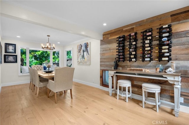 dining area with wooden walls, baseboards, hardwood / wood-style flooring, and a notable chandelier