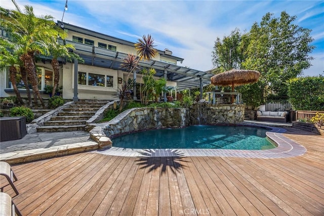 outdoor pool with central air condition unit, a pergola, outdoor lounge area, stairs, and a wooden deck