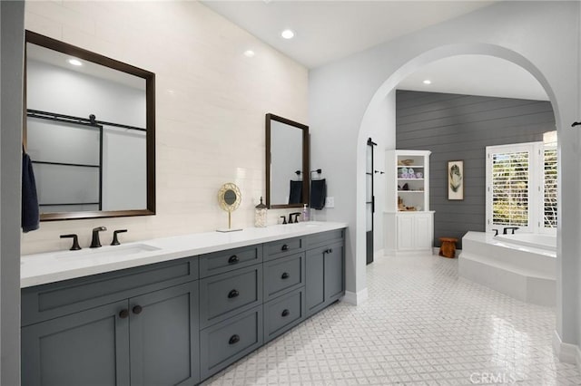 bathroom with a bath, wood walls, double vanity, and a sink