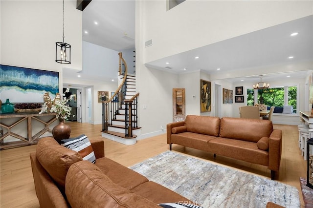 living room featuring a high ceiling, a chandelier, recessed lighting, wood finished floors, and stairs