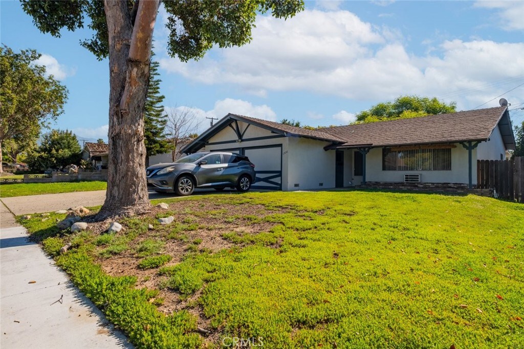 1936 Royalty Dr, Pomona, CA 91767 - ranch-style house with stucco siding, fence, driveway, a front lawn, and a garage