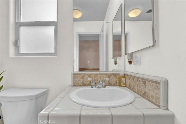 half bathroom featuring visible vents, toilet, and vanity