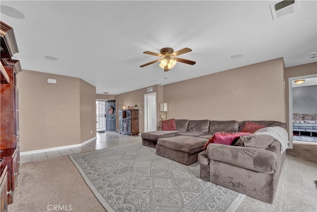 carpeted living area with tile patterned floors, ceiling fan, visible vents, and baseboards