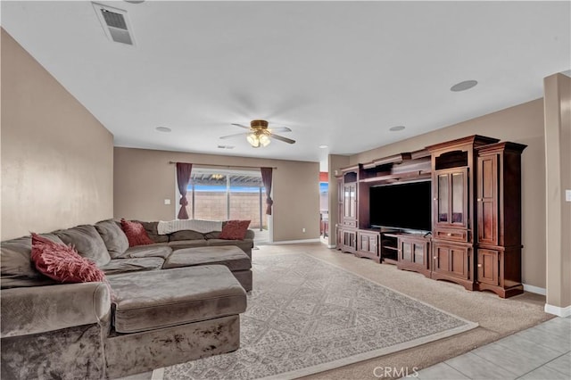 living room featuring light tile patterned flooring, visible vents, ceiling fan, and baseboards