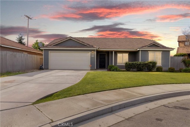 single story home with a yard, driveway, a tiled roof, an attached garage, and fence