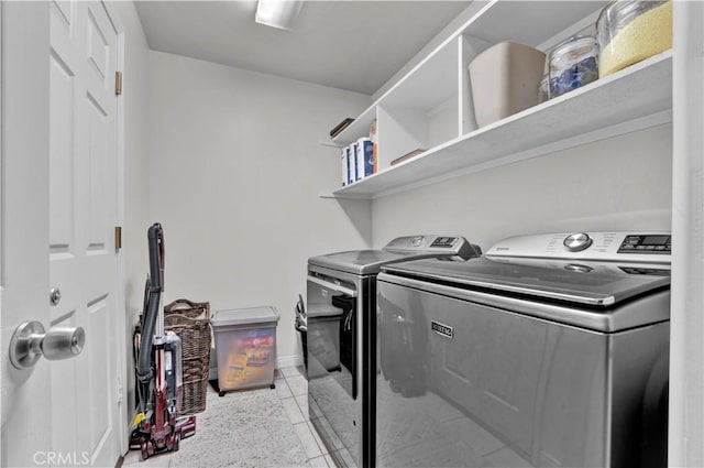 washroom with light tile patterned flooring, washer and dryer, laundry area, and baseboards