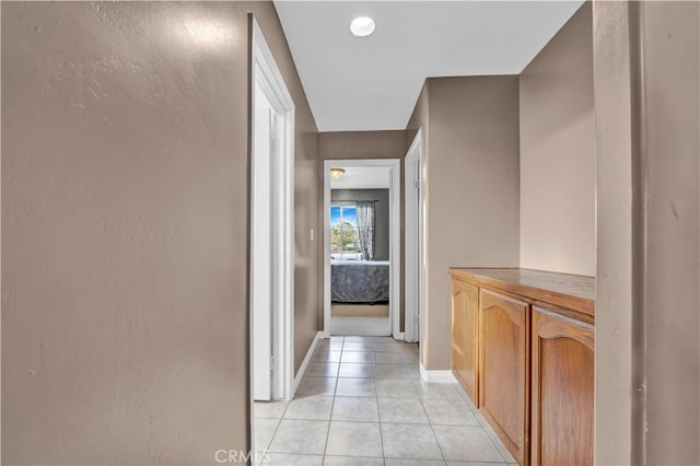hallway featuring baseboards and light tile patterned flooring