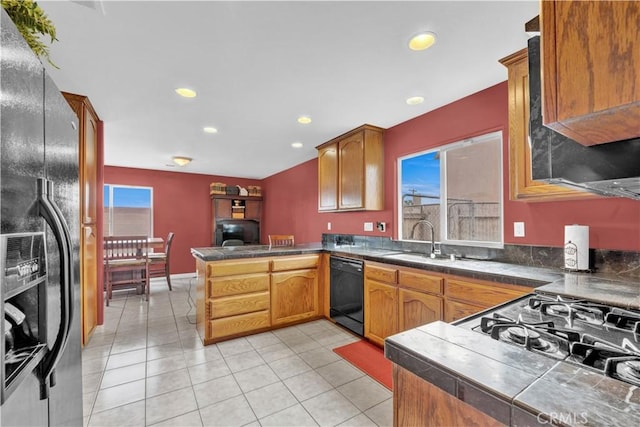 kitchen with recessed lighting, brown cabinetry, black appliances, a sink, and a peninsula