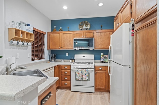 kitchen featuring white appliances, light wood-style floors, light countertops, brown cabinets, and a sink
