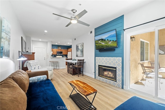 living room with ceiling fan, visible vents, a fireplace, light wood finished floors, and recessed lighting