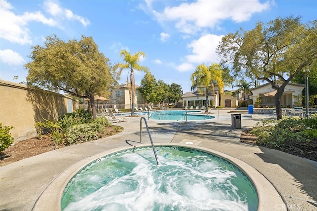community pool with fence, a hot tub, and a patio area