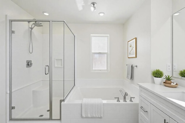 bathroom featuring vanity, a garden tub, and a shower stall
