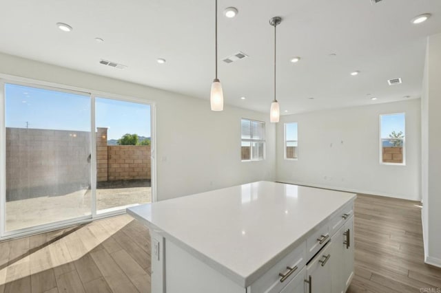 kitchen featuring visible vents, open floor plan, wood finished floors, and white cabinetry