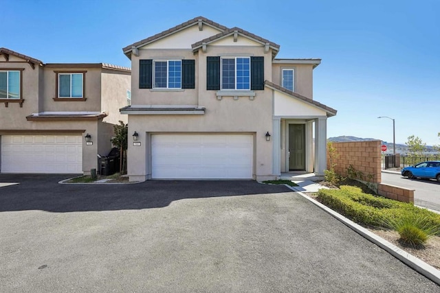 view of front facade featuring stucco siding, a tile roof, an attached garage, and aphalt driveway
