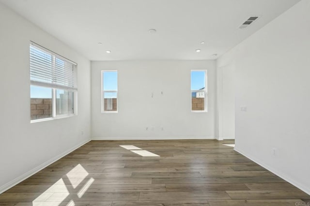 unfurnished room featuring recessed lighting, wood finished floors, visible vents, and baseboards