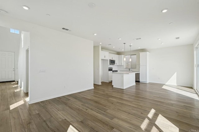 unfurnished living room with visible vents, wood finished floors, recessed lighting, baseboards, and a healthy amount of sunlight