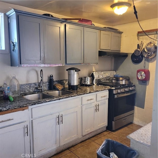 125 W Vernon Ave, Los Angeles, CA 90037 - kitchen featuring light tile patterned floors, gas range, under cabinet range hood, dark stone counters, and a sink