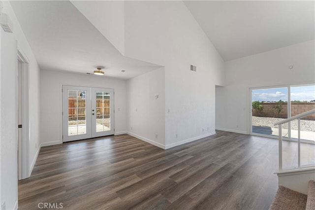 unfurnished living room featuring baseboards, a healthy amount of sunlight, a towering ceiling, and visible vents