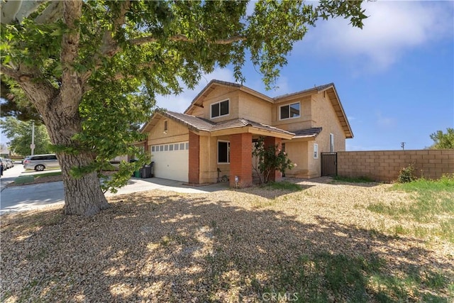 traditional-style home with a garage, concrete driveway, and fence