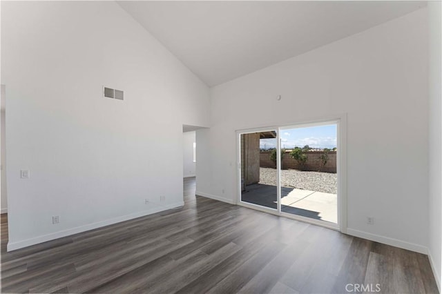 empty room with high vaulted ceiling, baseboards, and dark wood-type flooring