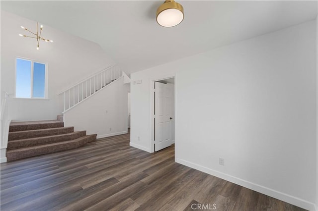 unfurnished living room with dark wood finished floors, lofted ceiling, baseboards, a chandelier, and stairs