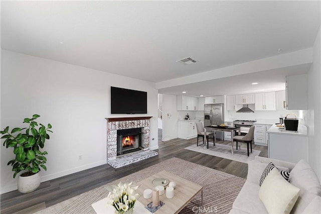 living room with recessed lighting, dark wood finished floors, visible vents, baseboards, and a fireplace