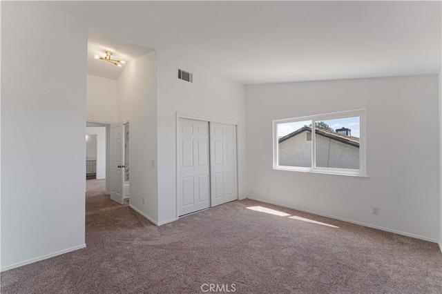 unfurnished bedroom with a closet, carpet floors, visible vents, and baseboards