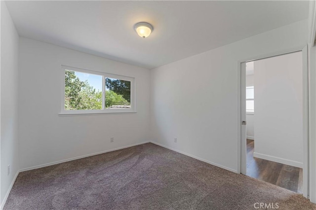 carpeted empty room featuring baseboards