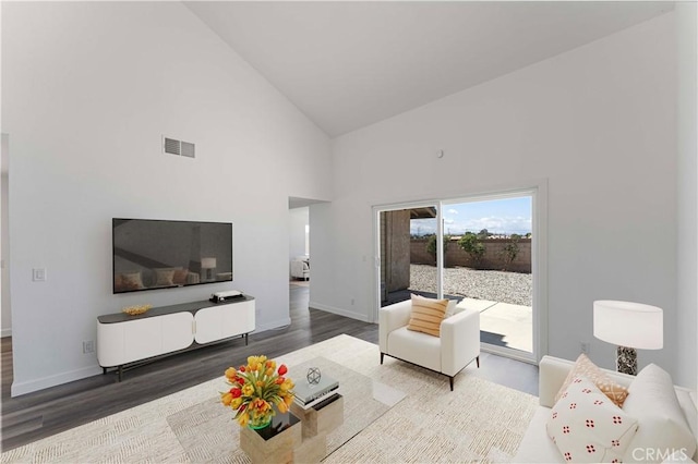 living area featuring baseboards, wood finished floors, visible vents, and high vaulted ceiling