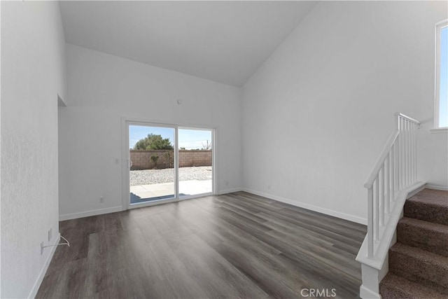 interior space featuring stairway, a wealth of natural light, high vaulted ceiling, and dark wood finished floors