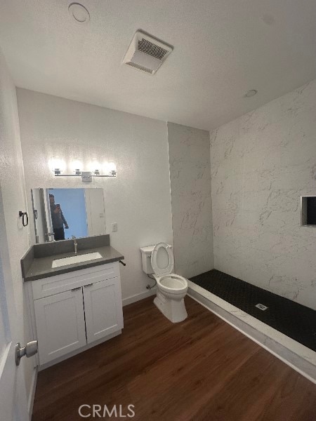 12929 Van Nuys Blvd, Pacoima, CA 91331 - bathroom featuring vanity, toilet, a textured ceiling, visible vents, and wood finished floors