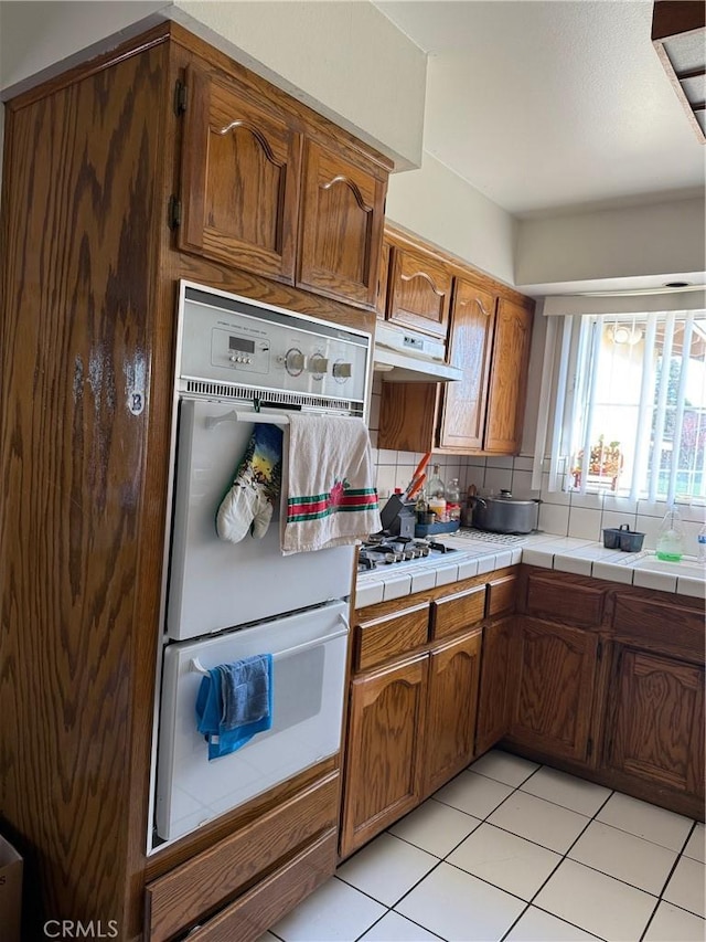 3816 Phaffle Dr, Bakersfield, CA 93309 - kitchen featuring double oven, light tile patterned flooring, brown cabinetry, and tile counters