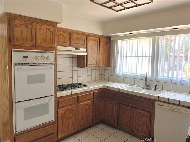 3816 Phaffle Dr, Bakersfield, CA 93309 - kitchen featuring white appliances, under cabinet range hood, brown cabinets, and tasteful backsplash