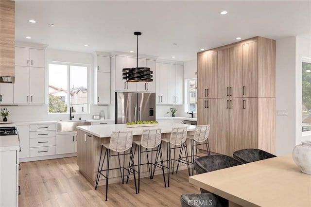 201 S Juanita Ave, Redondo Beach, CA 90277 - kitchen with stainless steel refrigerator with ice dispenser, a breakfast bar area, light wood-type flooring, a center island, and light countertops