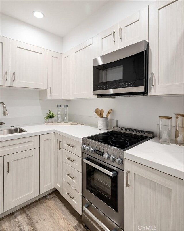 201 S Juanita Ave, Redondo Beach, CA 90277 - kitchen with appliances with stainless steel finishes, light wood finished floors, light countertops, recessed lighting, and white cabinetry