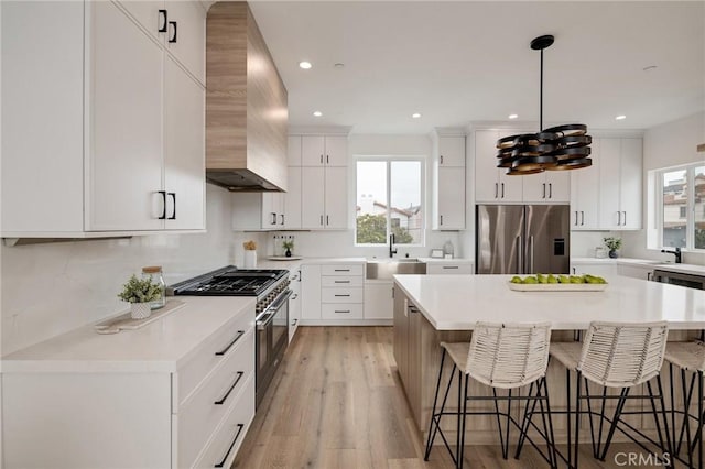 201 S Juanita Ave, Redondo Beach, CA 90277 - kitchen featuring stainless steel appliances, wall chimney exhaust hood, a kitchen breakfast bar, healthy amount of natural light, and recessed lighting