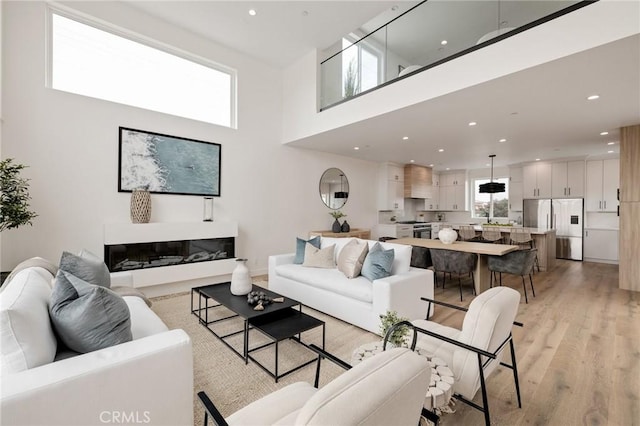 201 S Juanita Ave, Redondo Beach, CA 90277 - living room featuring light wood-type flooring, a high ceiling, recessed lighting, and a glass covered fireplace