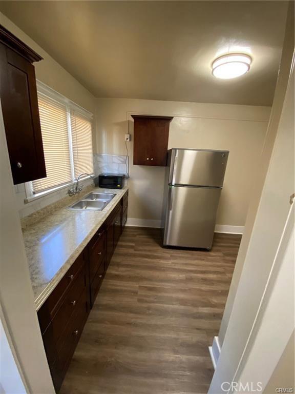 3030 W 12th Pl, Los Angeles, CA 90006 - kitchen with a sink, freestanding refrigerator, black microwave, baseboards, and dark wood-style flooring