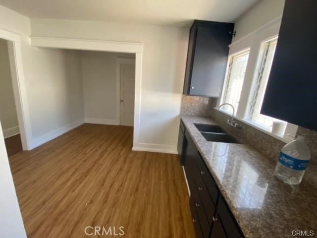 3030 W 12th Pl, Los Angeles, CA 90006 - kitchen featuring a sink, tasteful backsplash, baseboards, light wood-style floors, and light stone counters