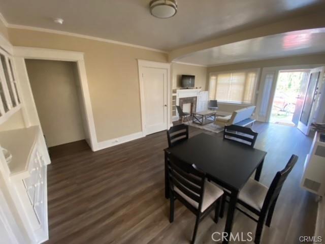 3030 W 12th Pl, Los Angeles, CA 90006 - dining area featuring baseboards, crown molding, dark wood-type flooring, and a fireplace
